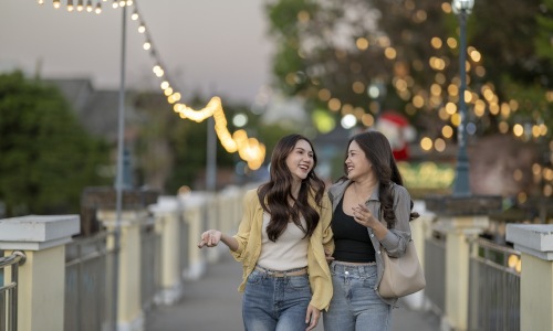 Two women walking down a walkway at dusk